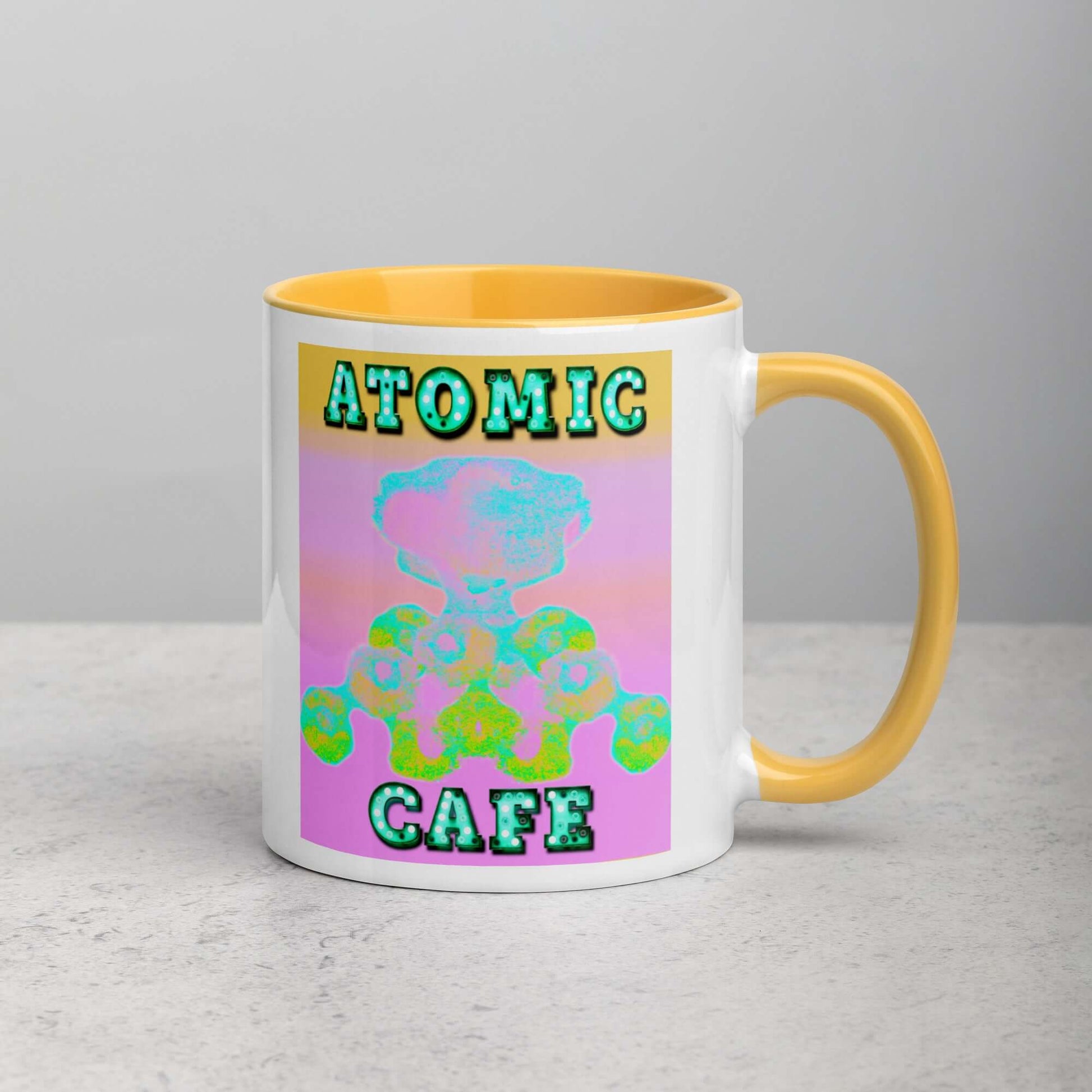 Pastel Atomic Blast with “Atomic Cafe” in Marquee Letters Mug with Golden Yellow Color Inside Right Handed Front View